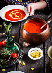 Tomato cream soup with croutons in female hands.