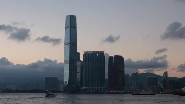 Tall skyscrapers on Kowloon side of Hong Kong at sunset. Moving clouds timelapse