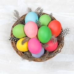 Easter eggs in basket over bright wooden background
