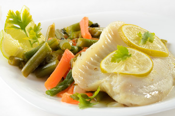 Tilapia fish baked with herbs and lime served on white plate wit