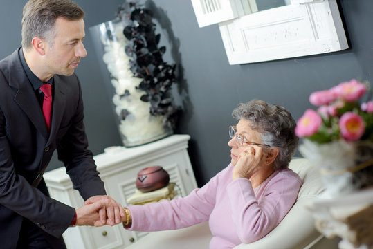 Funeral director holding hand of elderly lady