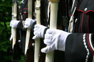 Closup detailed photoof the soldiers hands in gloves on a bayonet rifle in rest position during a military parade. Selective focus