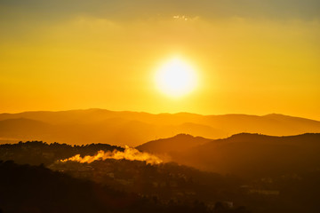 Sunset over the mountains with the smoke from the house