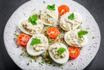 Deviled eggs with mushrooms, mayonnaise and cherry tomatoes on cress sprouts