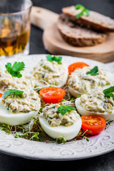 Deviled eggs with mushrooms, mayonnaise and cherry tomatoes on cress sprouts
