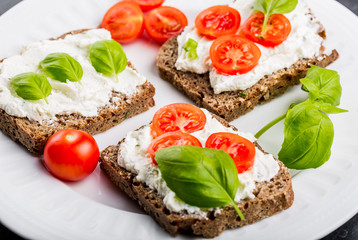 Sandwiches with soft cream cheese, cherry tomatoes and fresh basi