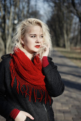 High fashion blonde girl with the red lips in the red scarf in the park outdoor