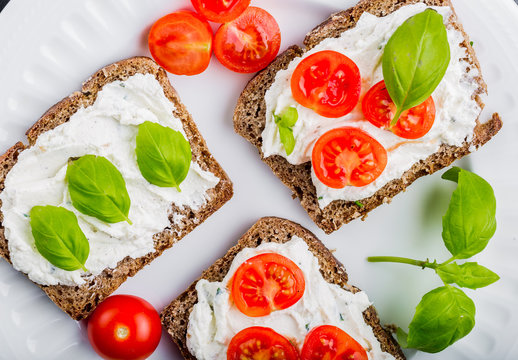 Sandwiches with soft cream cheese, cherry tomatoes and fresh basi