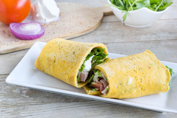 Egg wrap cut in half, filled with a lof of vegetables.