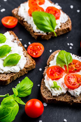 Sandwiches with soft cream cheese, cherry tomatoes and fresh basi