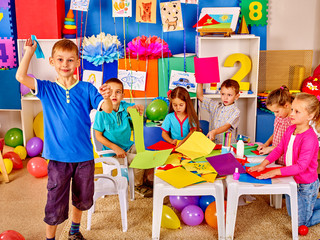 Group kids playing with origami airplane together in kindergarten . 