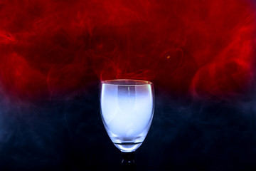 Hookah colorful smoke in the cocktail glass over black background. Abstract art.