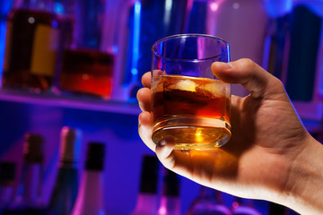 Man hand with whiskey glass in bar 