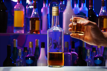 Fototapeta na wymiar Whiskey bottle and glass in men's hand 