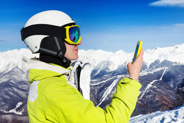 Fototapeta na wymiar Skier woman with cell phone over mountains