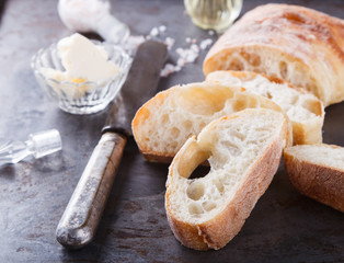 Italian ciabatta bread cut in slices on chopping board with butter,olive oil and salt.selective focus.
