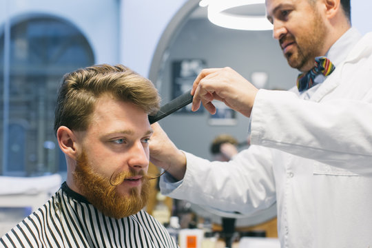 Hairdresser combing and cutting hair