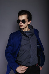 Vogue handsome man in the jacket and sunglasses in the studio