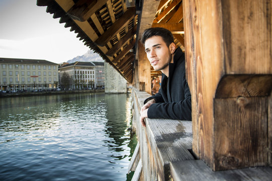 Young man standing on wooden footbridge in Switzerland while looking away