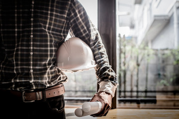 Smart Businessman holding construction helmet and blueprints in