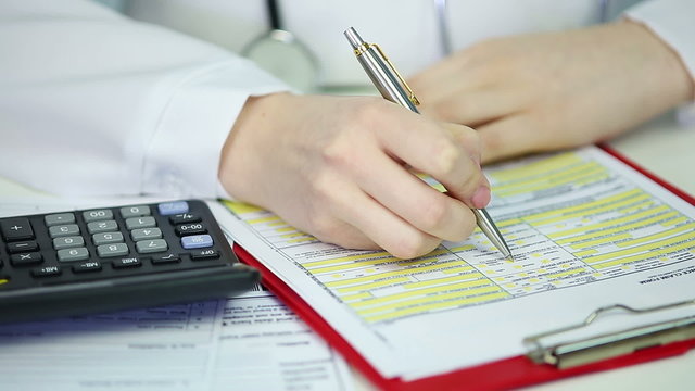 Female therapist filling out health insurance claim form, calculating expenses
