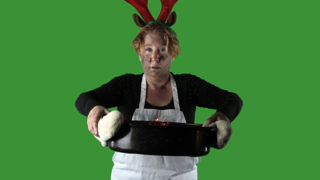 Woman wearing apron with reindeer antlers holding buring roasting pan,