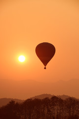 Colorful hot air balloon is flying at sunset.