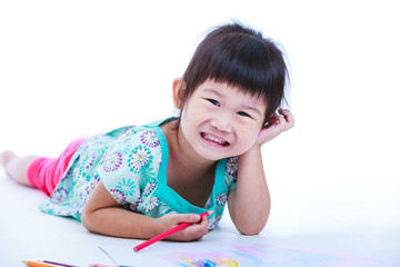 Child lie on the floor drawing on paper and smiling. On white