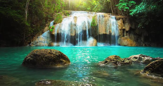 Idyllic waterfall and amazing nature. Sunlight and wild pond in jungle forest