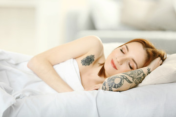 Obraz premium Attractive woman with tattoo lying on the bed