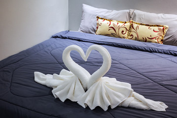 Fototapeta na wymiar towel folded in swan shape on bed sheet