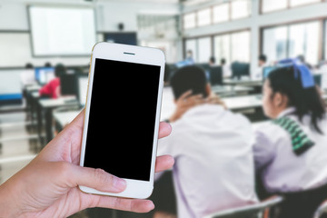 Hands woman are holding touch screen smart phone,tablet on blurred Defocused student study computer classroom  background.