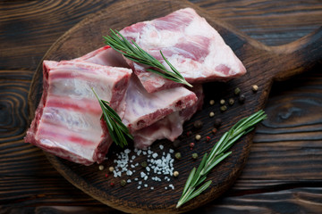 Rustic wooden chopping board with raw seasoned pork ribs