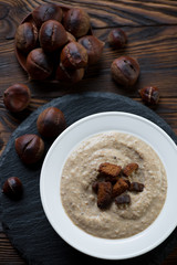 Chestnut cream-soup with croutons in a glass plate, top view