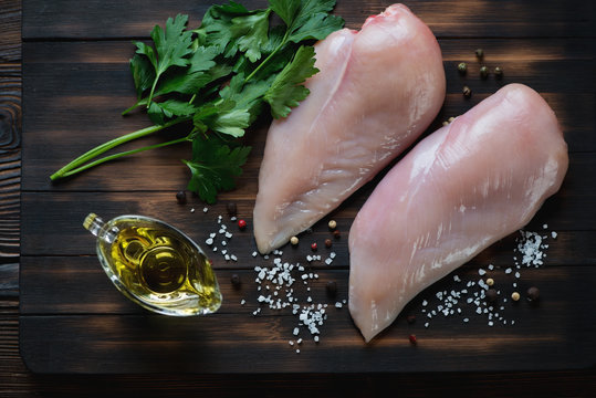 Raw chicken breasts with parsley, olive oil, salt and pepper