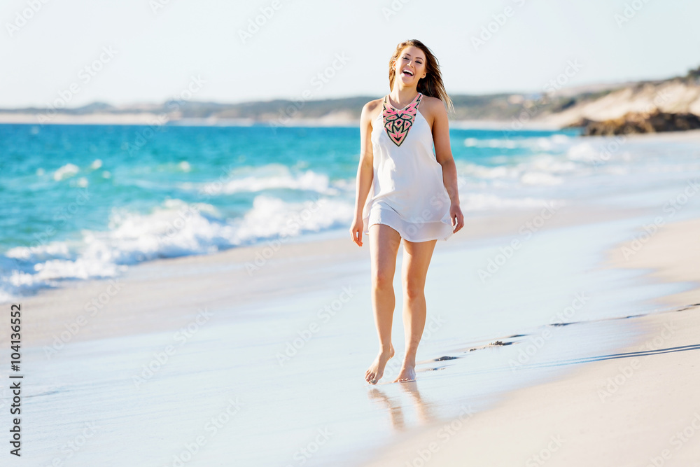 Poster Young woman walking along the beach