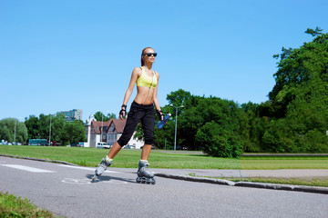 Young, beautiful, sporty and fit girl rollerblading on inline skates