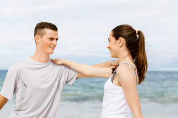 Runners. Young couple exercising and stertching on beach