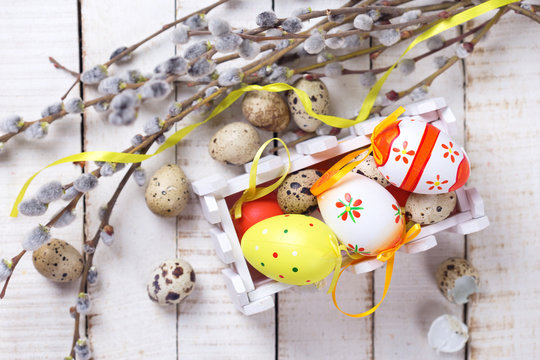 Colorful easter eggs in box, willow  branches on wooden backgrou