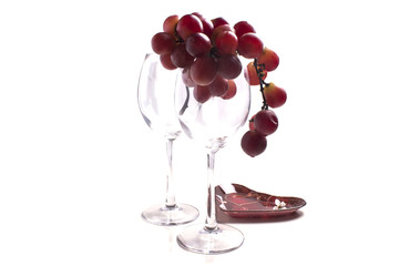 a bunch of grapes on a saucer near the empty glasses