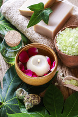 Bowl of green sea salt, floating candle among rose petals