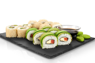Sushi rolls with avocado, salmon and sesame seeds on slate tray.