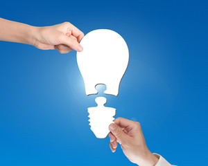 Woman and man two hands assembling one bulb shape puzzle