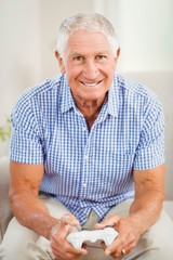 Senior man holding joystick and looking at camera