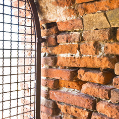 Rusty metal grate against a brick wall of an italian building