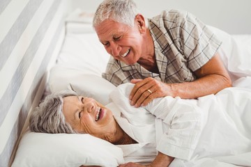 Happy senior couple laughing on bed