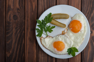 Fried eggs in a plate on a wooden background
