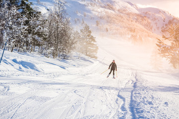 Woman with long brown hair skiing in ski centre, stryn norway early in the morning with fog and...