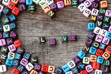 Cubes with letters arranged in love pattern with word LOVE in the middle on wooden table