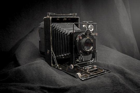 Antique old photo camera isolated on black fabrick background. Old folding 'vest pocket' film camera.
